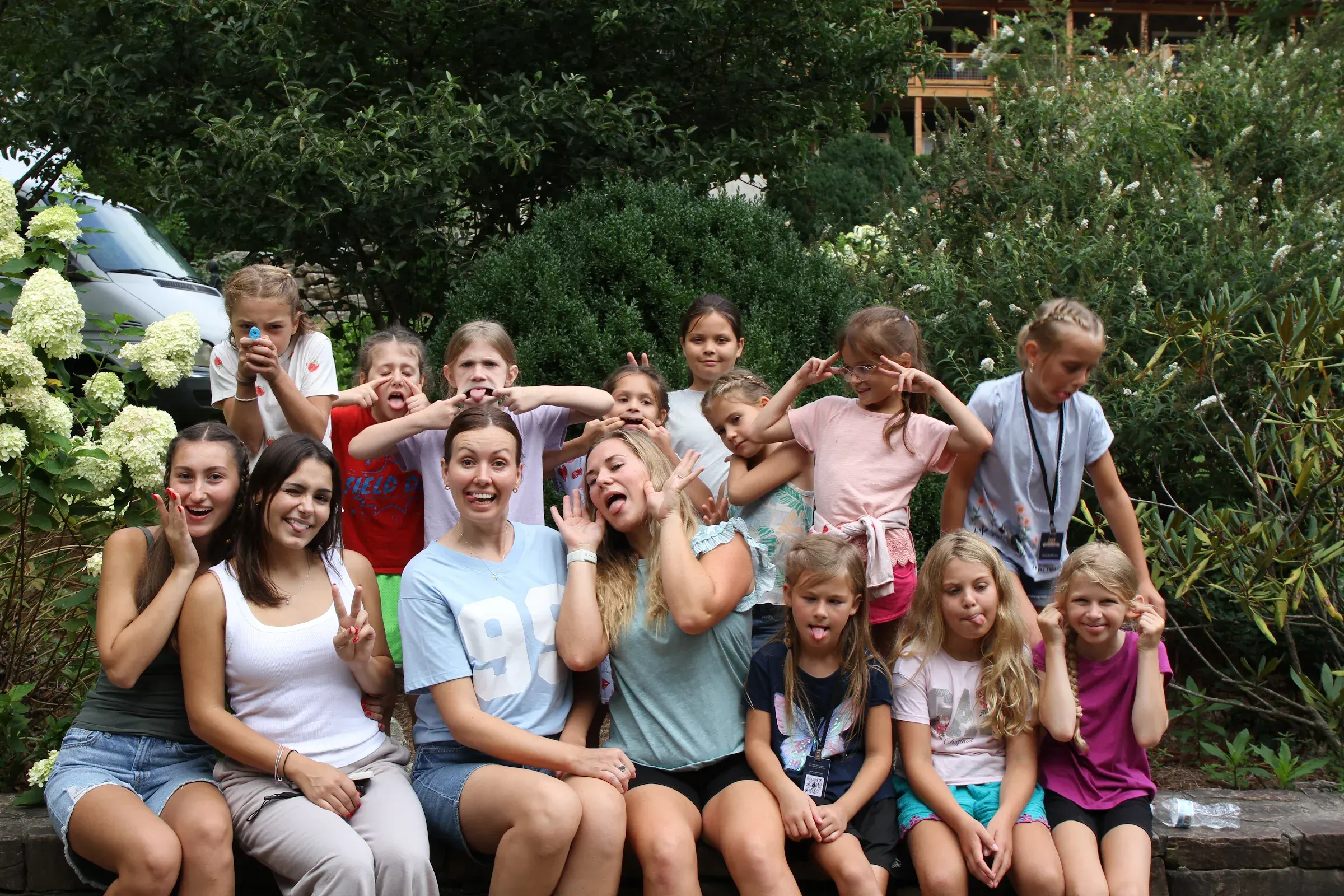 Girls and their leaders crowd together, laughing and smiling for a cabin photo.
