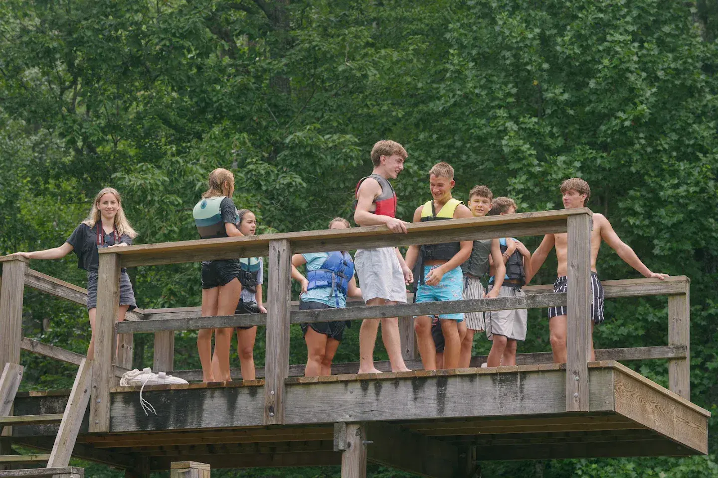 Campers in life jackets smile together on the lake deck before a swim.